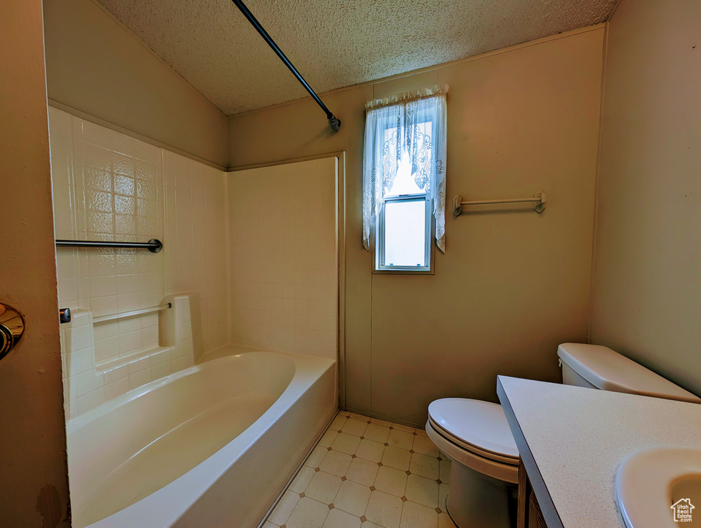 Full bathroom featuring a textured ceiling, shower / bathing tub combination, tile floors, toilet, and vanity