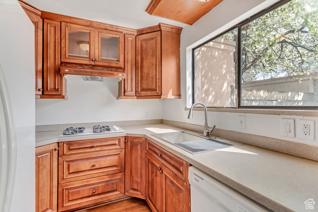 Kitchen with custom range hood, white appliances, sink, and light wood-type flooring