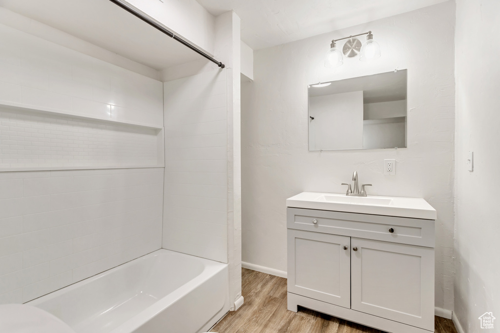 Bathroom featuring vanity with extensive cabinet space, tiled shower / bath combo, and hardwood / wood-style flooring