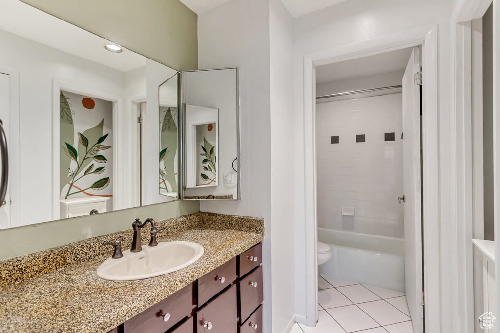 Full bathroom featuring tile floors, oversized vanity, tiled shower / bath, and toilet