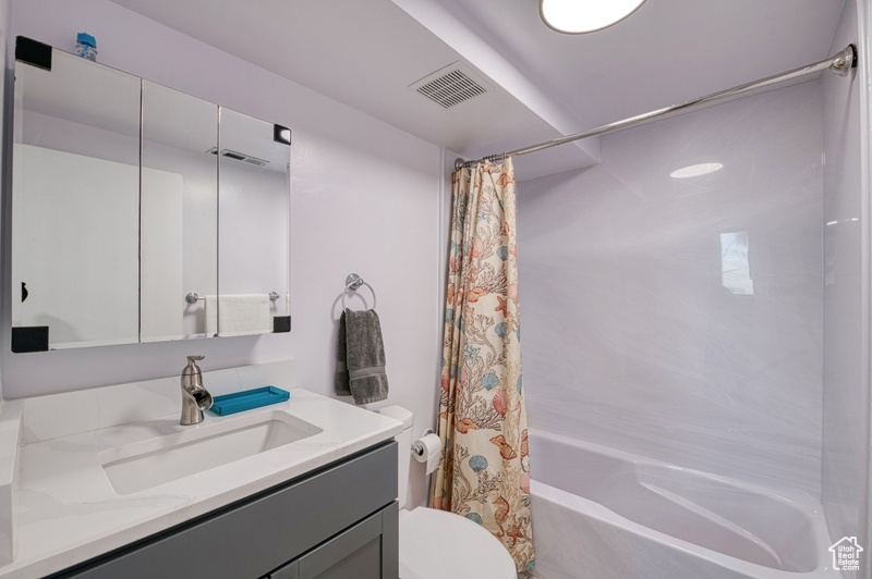 Full bathroom featuring oversized vanity, toilet, and shower / bath combo with shower curtain