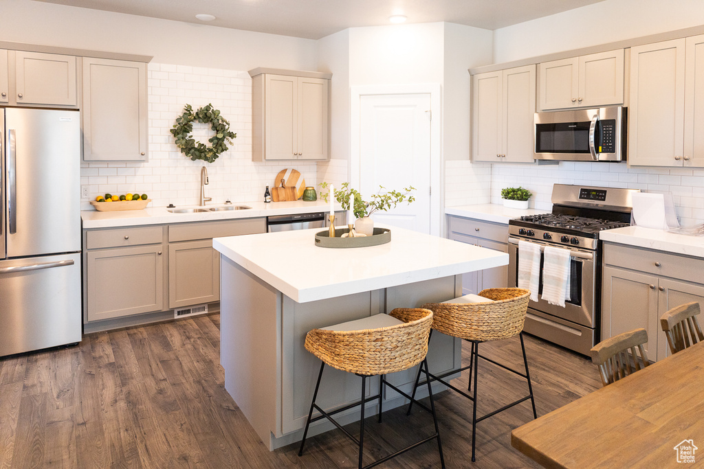 Kitchen featuring sink, tasteful backsplash, a breakfast bar area, stainless steel appliances, and dark hardwood / wood-style floors