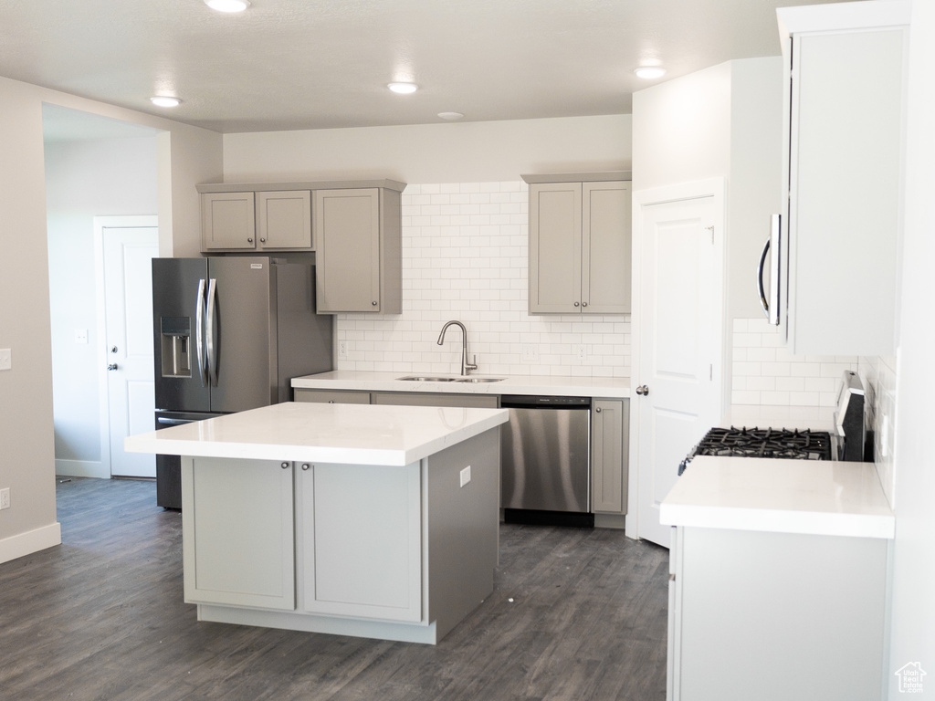 Kitchen featuring sink, stainless steel appliances, a center island, and dark hardwood / wood-style flooring