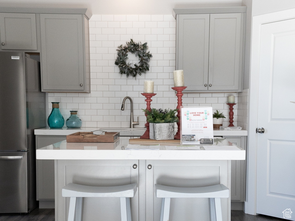 Kitchen with tasteful backsplash, gray cabinets, dark hardwood / wood-style flooring, and stainless steel fridge