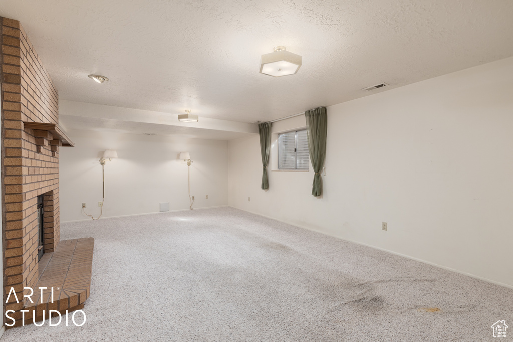 Unfurnished living room with a fireplace, carpet, and a textured ceiling