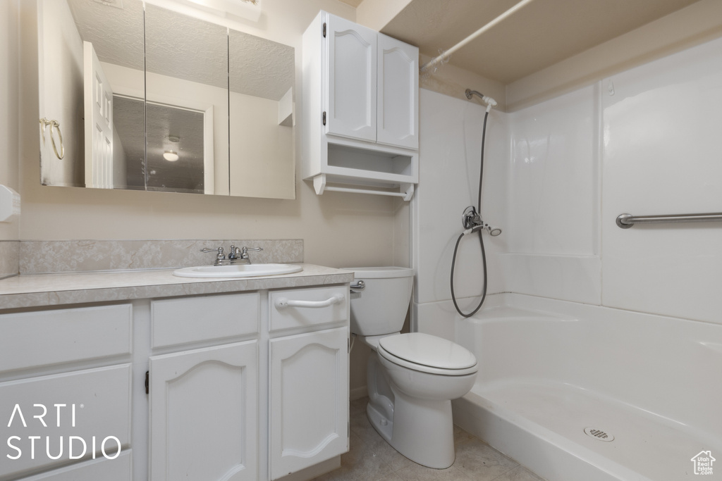 Bathroom with vanity with extensive cabinet space, toilet, and a textured ceiling
