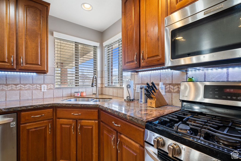 Kitchen with tasteful backsplash, dark stone counters, stainless steel appliances, and sink