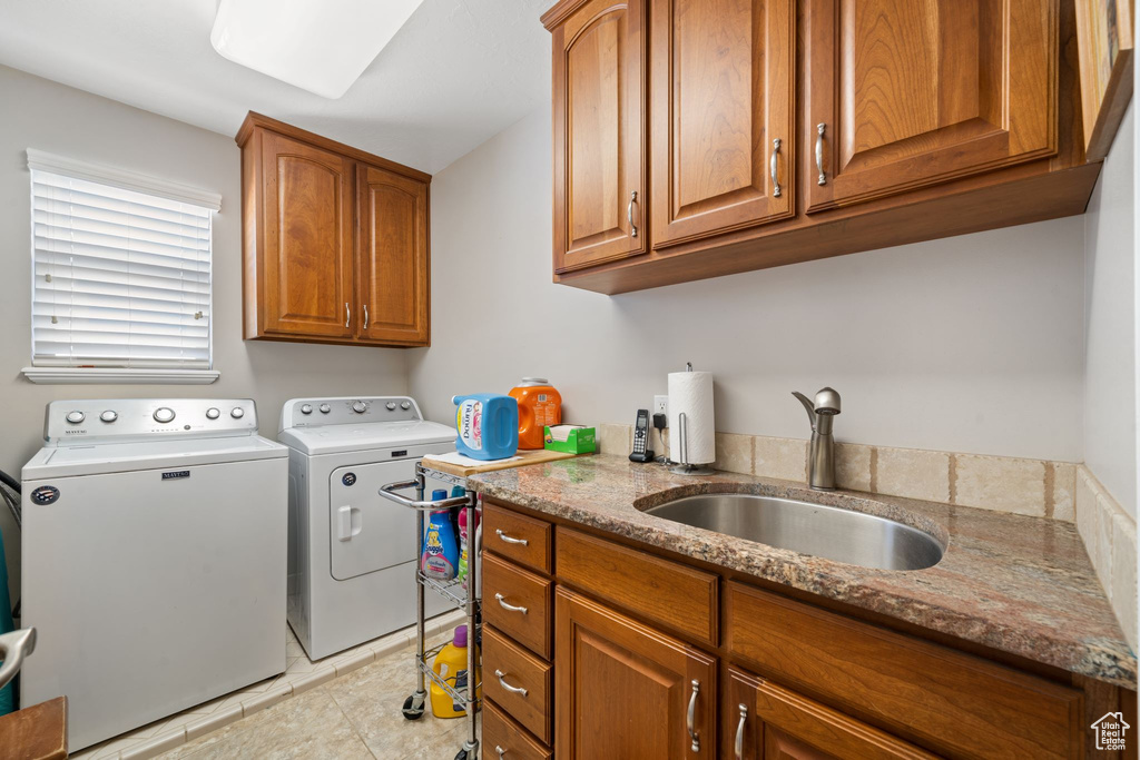 Laundry room featuring sink, light tile floors, cabinets, and washer and clothes dryer