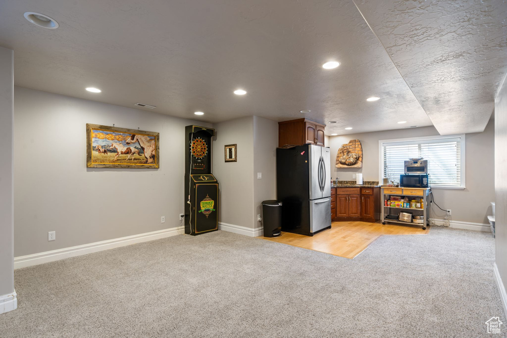 Kitchen featuring stainless steel refrigerator, light carpet, and stone countertops
