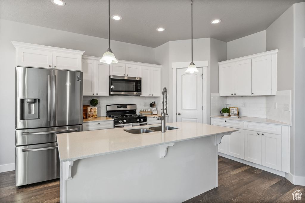 Kitchen with tasteful backsplash, pendant lighting, stainless steel appliances, and dark wood-type flooring