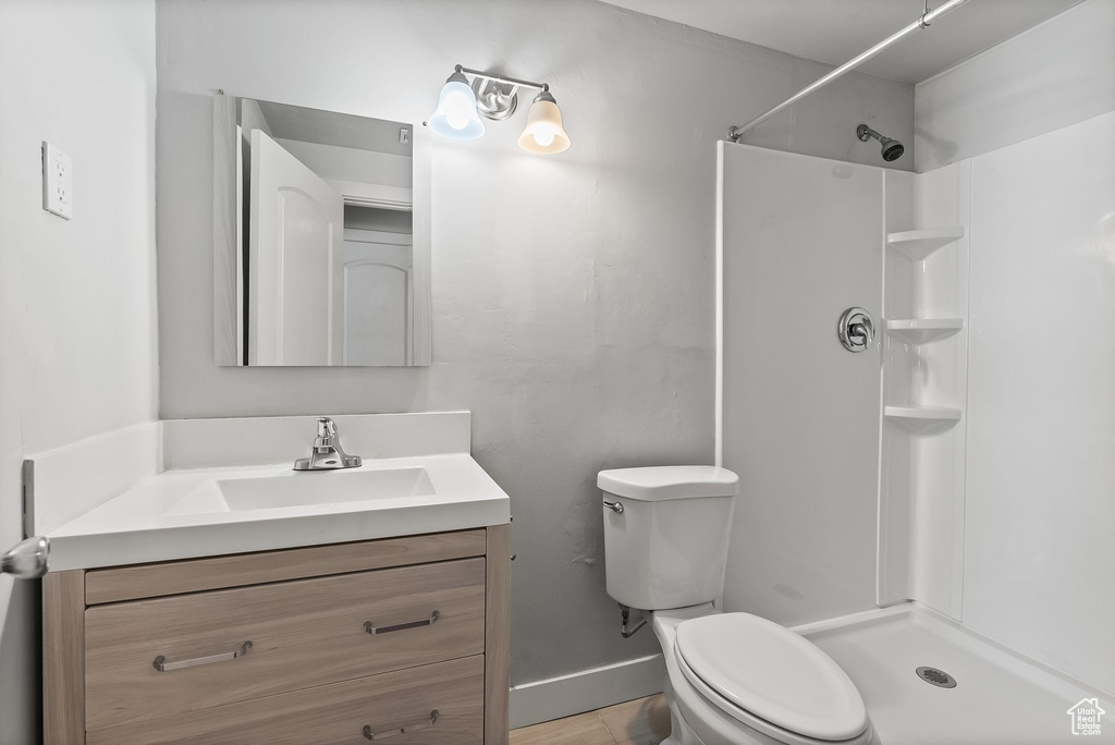 Bathroom with a shower, vanity, tile floors, and toilet