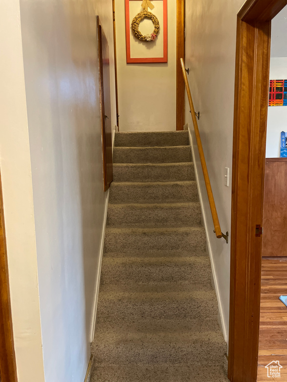Staircase featuring dark carpet