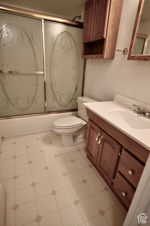 Full bathroom with bath / shower combo with glass door, toilet, tile flooring, and vanity