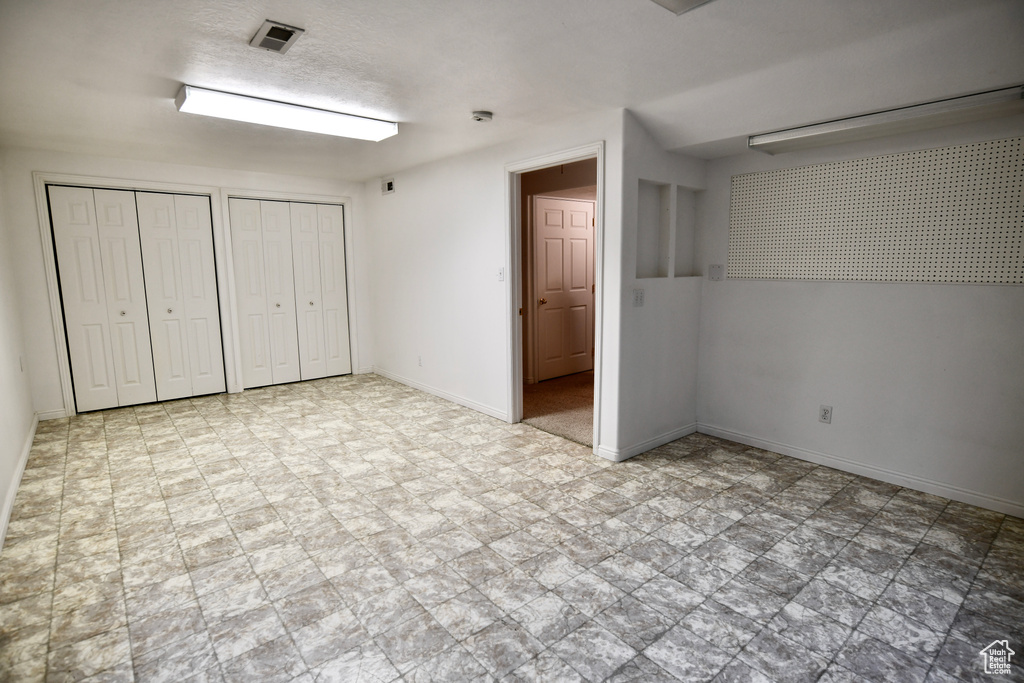 Unfurnished bedroom featuring light tile floors and multiple closets