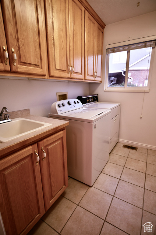 Laundry area with independent washer and dryer, sink, cabinets, and light tile floors