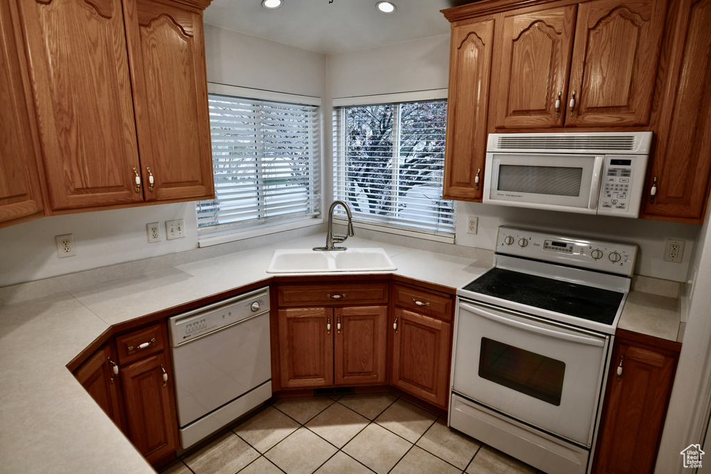 Kitchen with sink, white appliances, and light tile floors