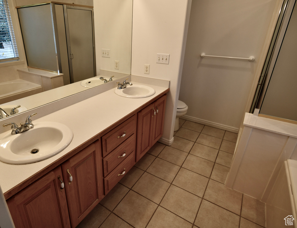 Full bathroom featuring double sink, toilet, tile floors, and oversized vanity