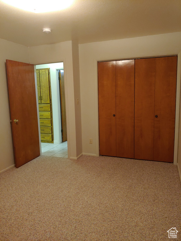 Unfurnished bedroom with light carpet, ensuite bath, and a closet