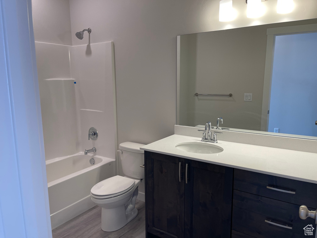 Full bathroom featuring toilet, oversized vanity, hardwood / wood-style floors, and bathing tub / shower combination