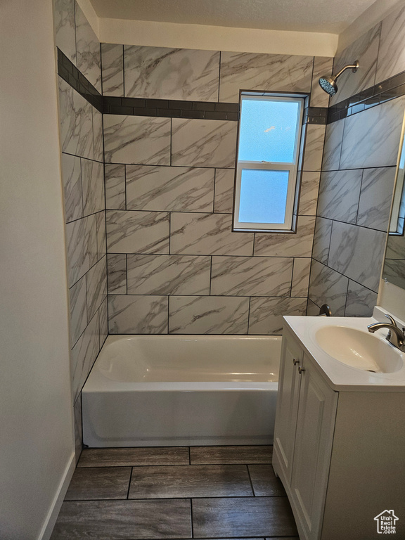 Bathroom with tiled shower / bath combo, vanity, and tile flooring