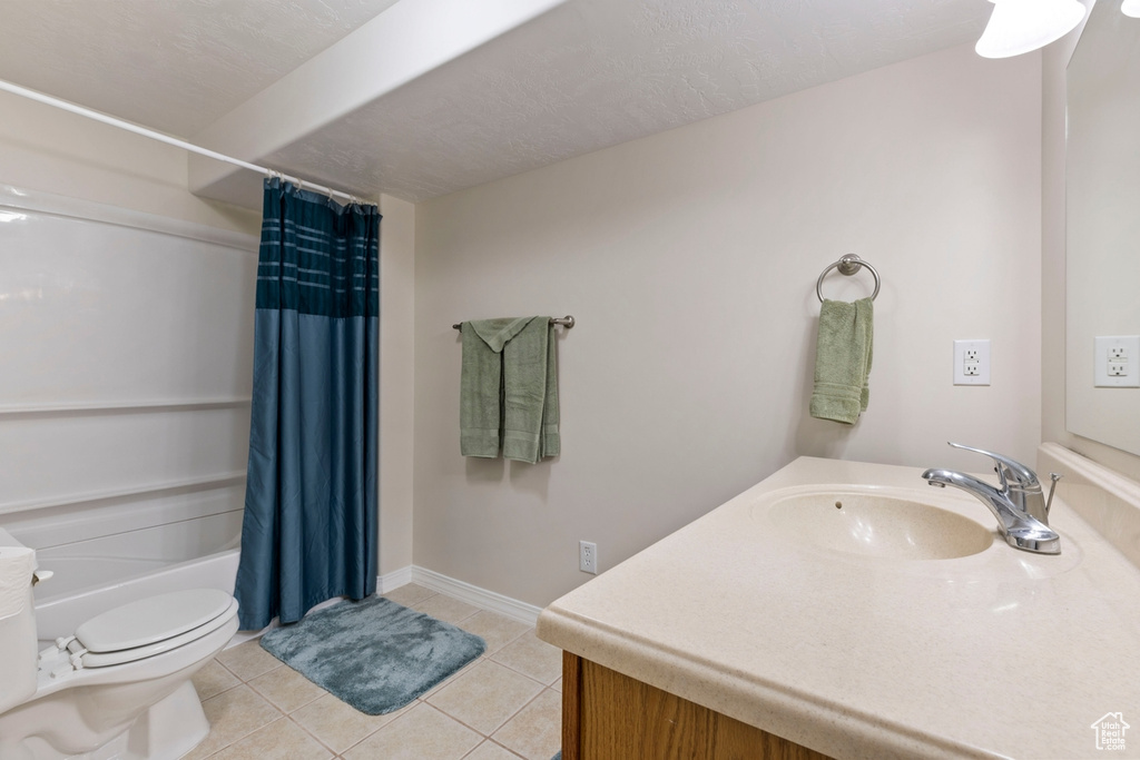 Full bathroom with tile floors, toilet, shower / bath combination with curtain, and vanity