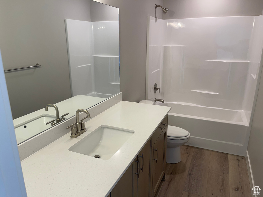Full bathroom featuring wood-type flooring, oversized vanity, shower / bathing tub combination, and toilet