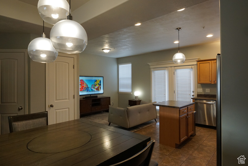 Kitchen with dark tile flooring, a center island, dishwasher, and decorative light fixtures