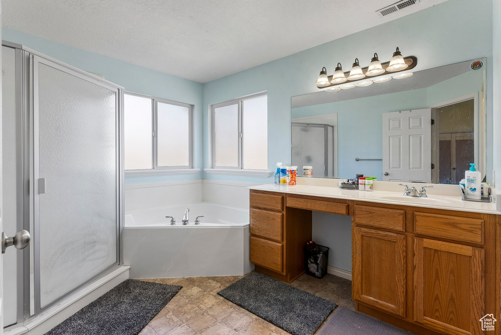 Bathroom featuring tile flooring, vanity, and shower with separate bathtub