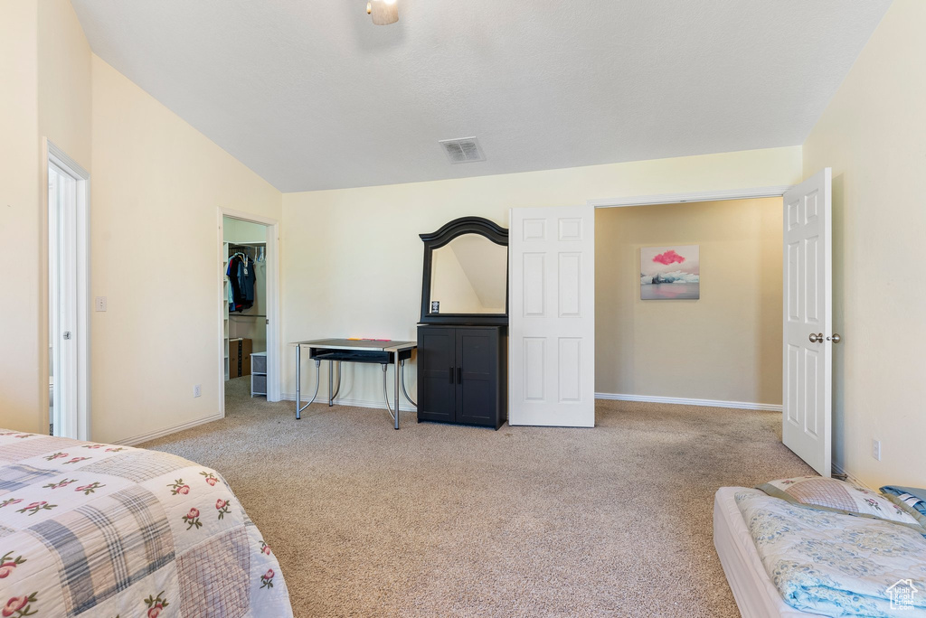 Bedroom featuring light colored carpet, a closet, a walk in closet, and lofted ceiling