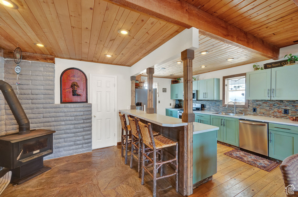 Kitchen with log walls, backsplash, beam ceiling, stainless steel appliances, and wooden ceiling