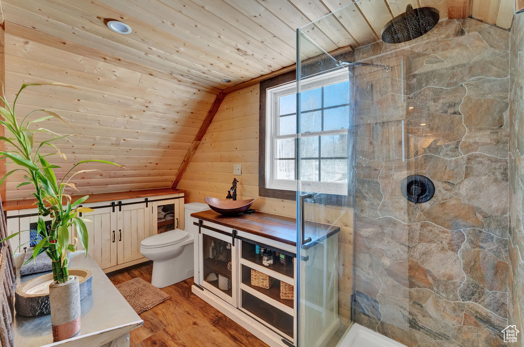 Bathroom featuring wooden ceiling, toilet, tiled shower, and wooden walls