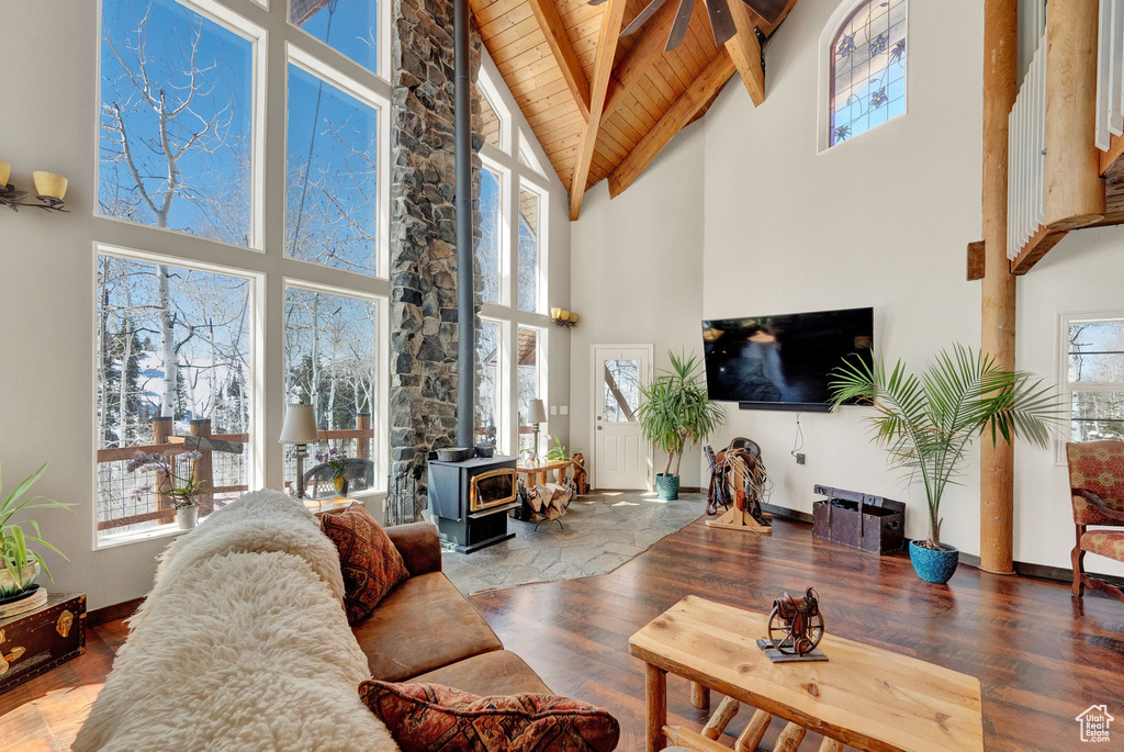Living room with a wood stove, dark hardwood / wood-style floors, high vaulted ceiling, and wooden ceiling