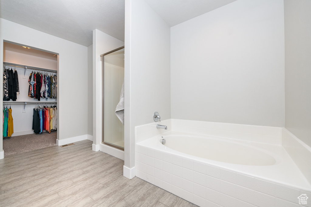 Bathroom featuring wood-type flooring and shower with separate bathtub