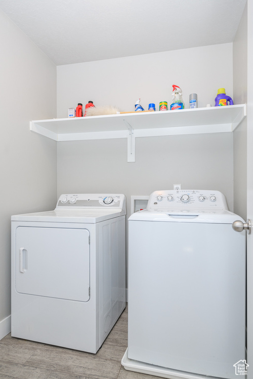 Laundry room with hookup for a washing machine, washing machine and clothes dryer, and light wood-type flooring