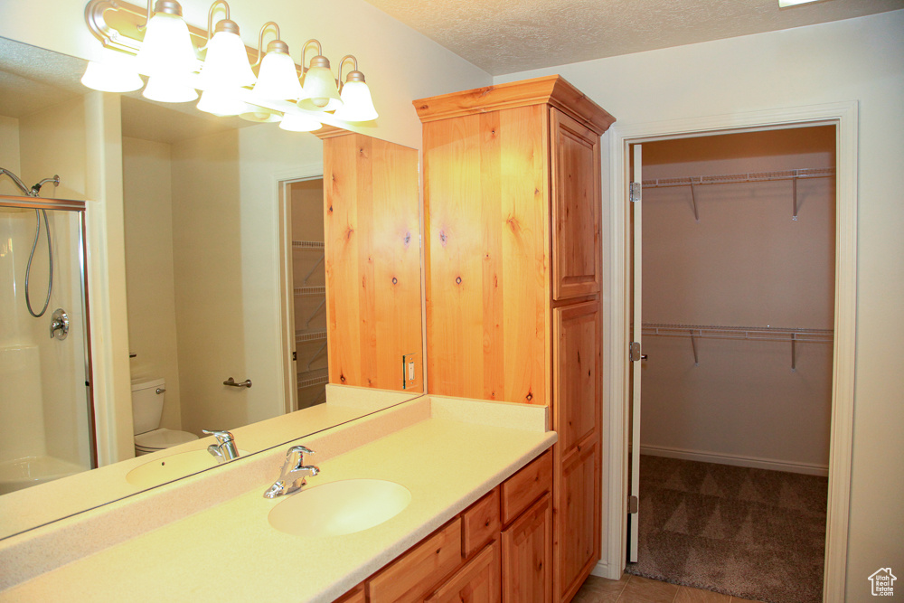 Bathroom featuring a textured ceiling, vanity with extensive cabinet space, and toilet