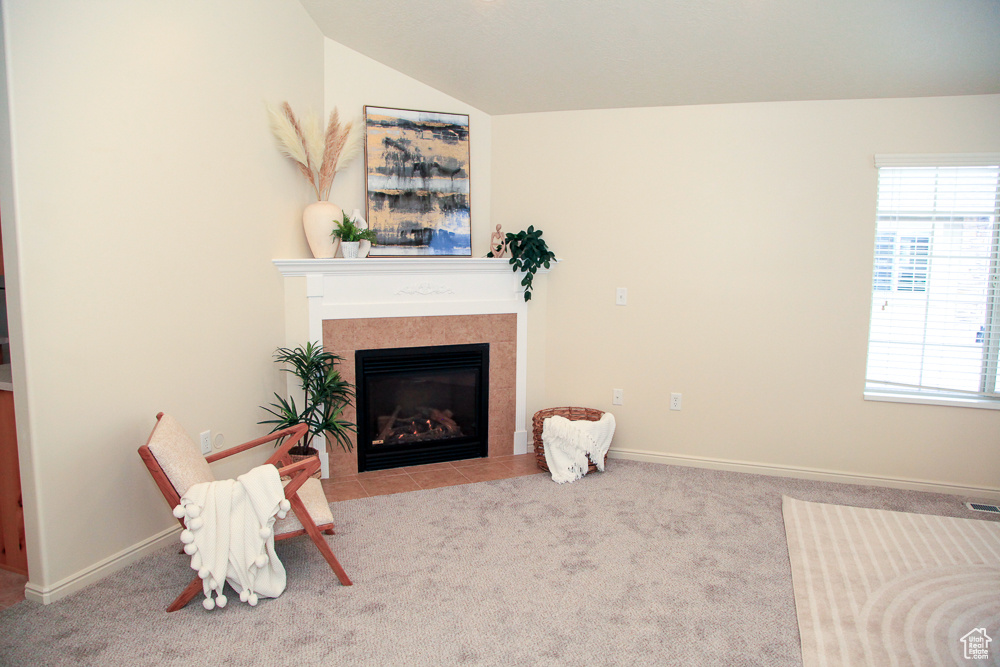 Living room with light colored carpet, a fireplace, and vaulted ceiling