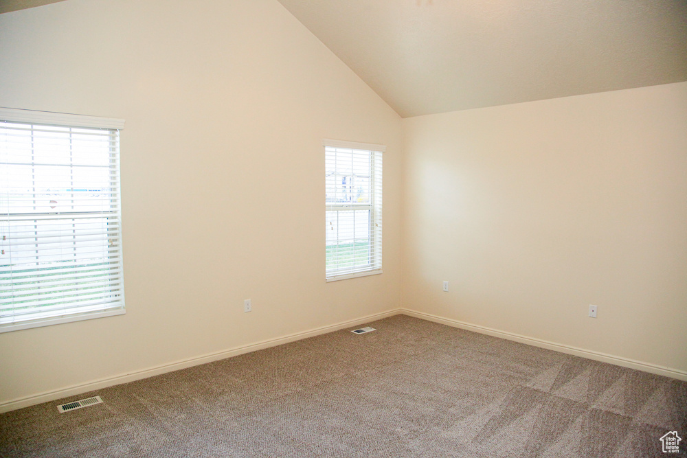 Unfurnished room with light carpet and high vaulted ceiling