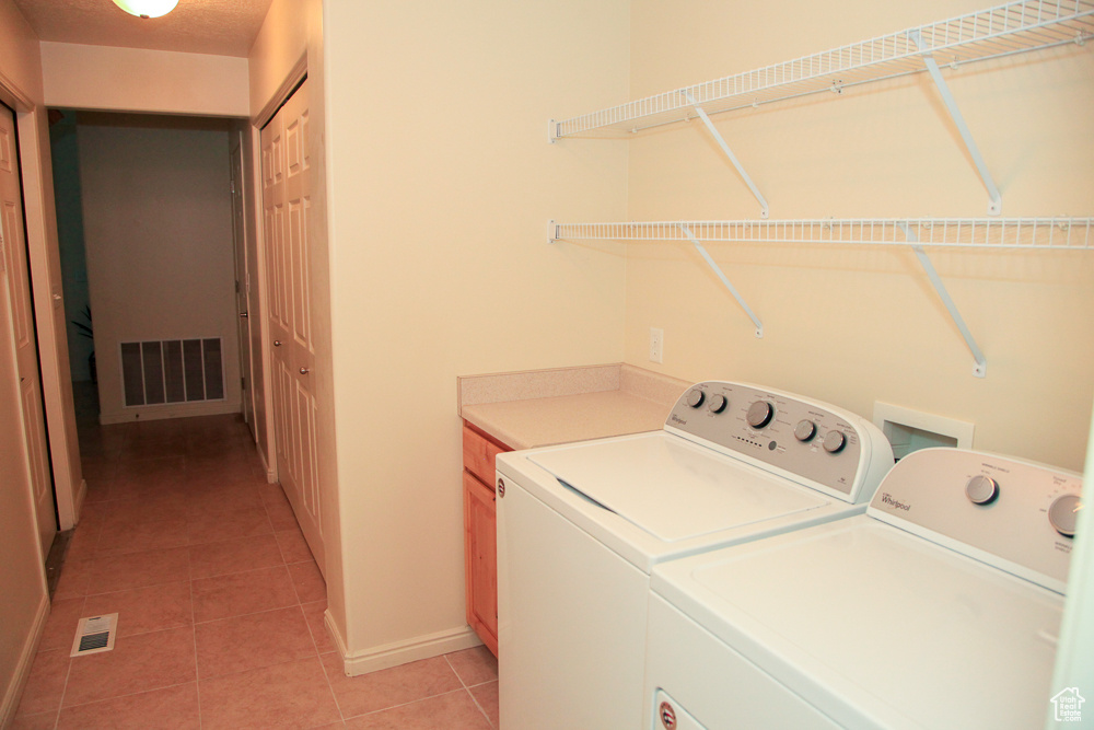 Washroom with cabinets, light tile floors, and washer and dryer