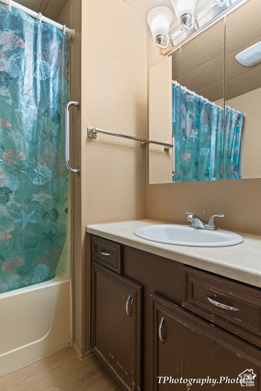 Bathroom featuring hardwood / wood-style floors, vanity, and shower / bath combo with shower curtain