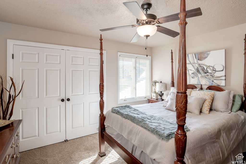 Carpeted bedroom featuring a closet, a textured ceiling, and ceiling fan