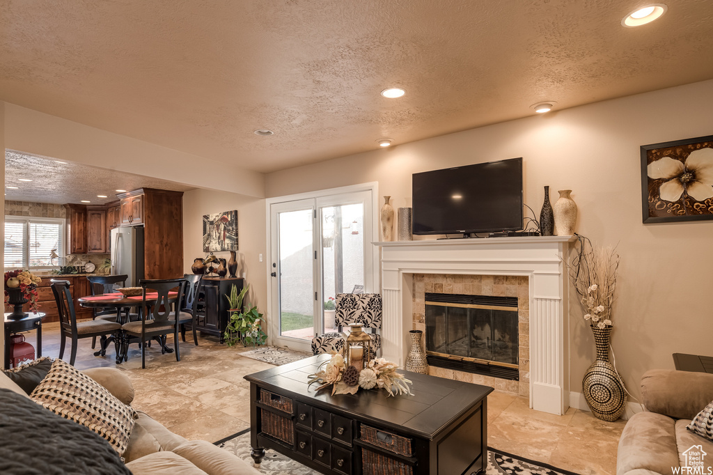 Living room with light tile flooring, a textured ceiling, and a fireplace