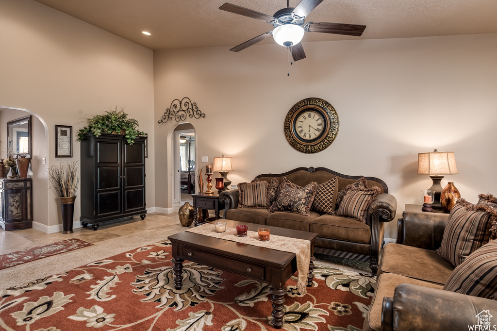 Living room featuring a textured ceiling, high vaulted ceiling, ceiling fan, and light tile flooring