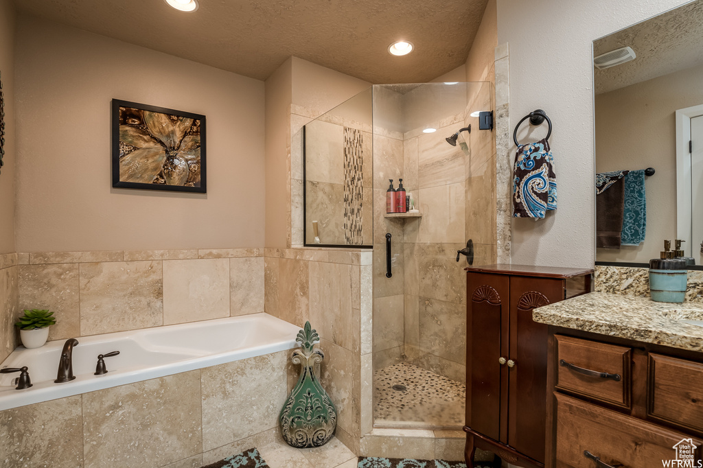 Bathroom with vanity, separate shower and tub, and a textured ceiling