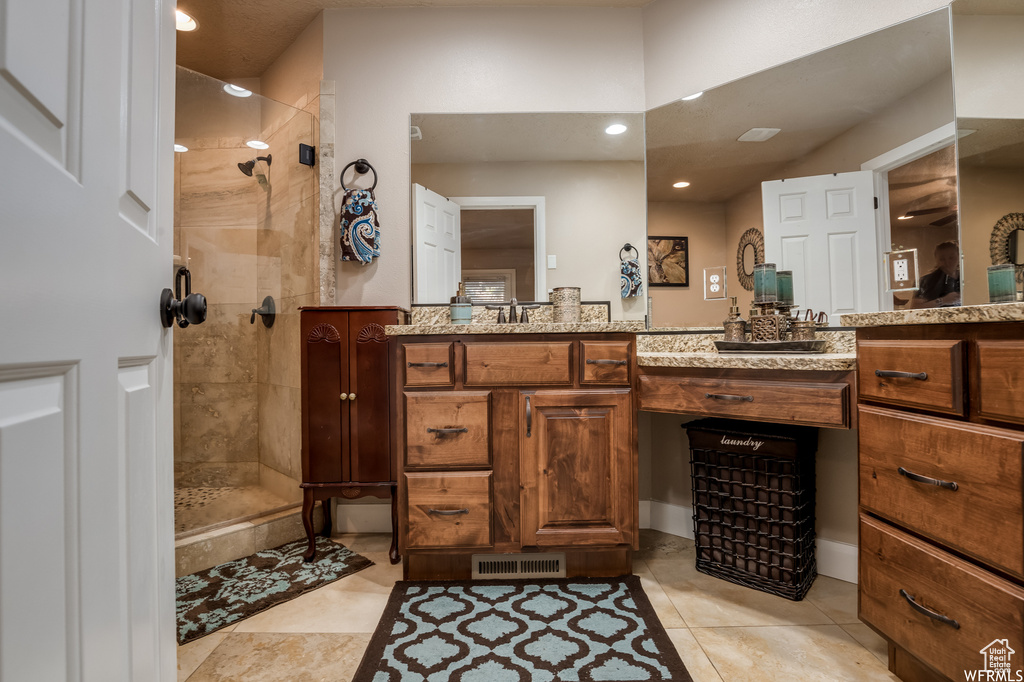 Bathroom with tiled shower, vanity, and tile floors