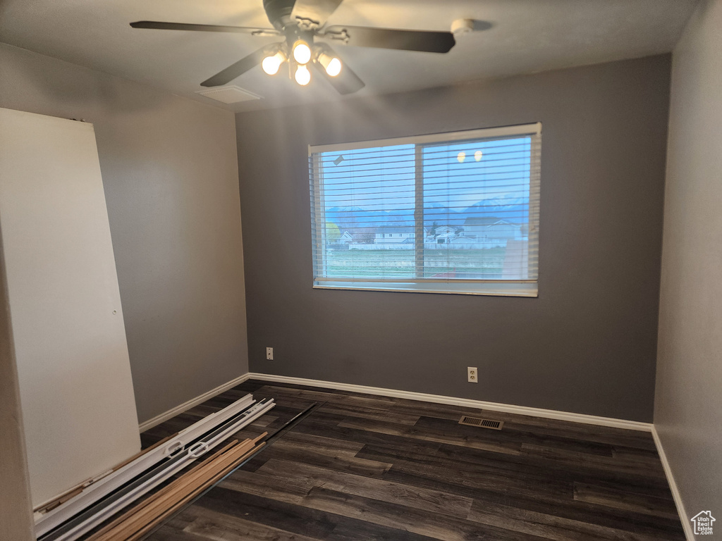 Empty room with ceiling fan and dark hardwood / wood-style floors