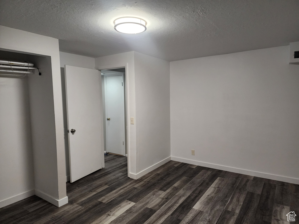 Unfurnished bedroom with dark hardwood / wood-style floors, a closet, and a textured ceiling