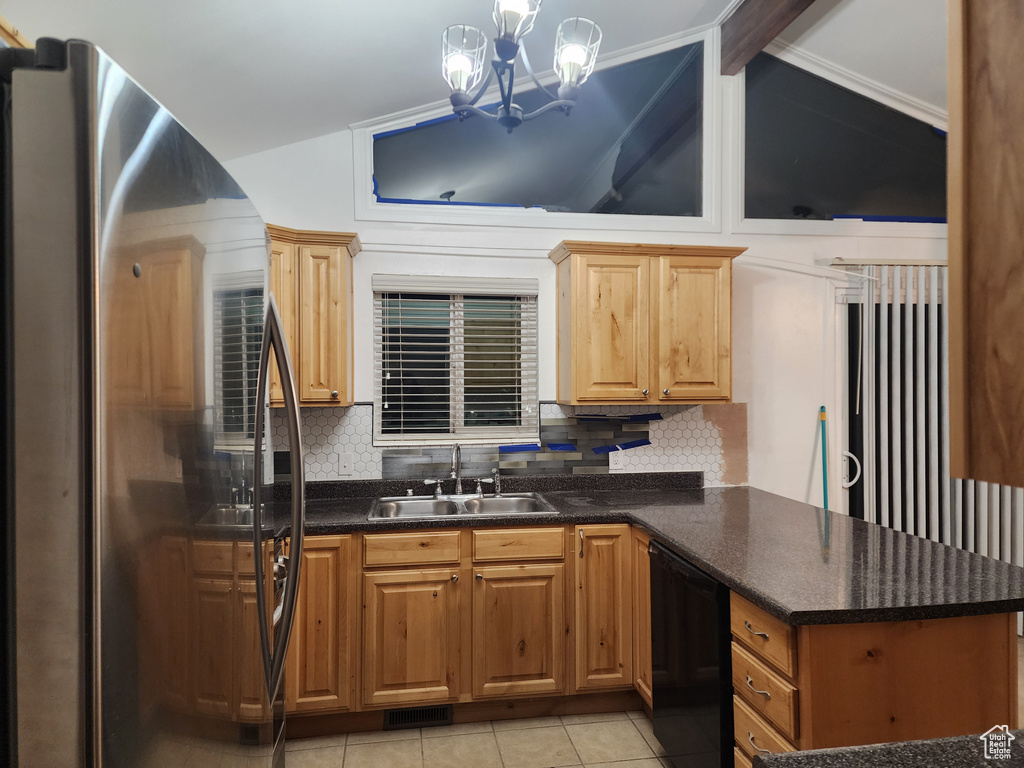 Kitchen featuring sink, dishwasher, backsplash, stainless steel refrigerator, and an inviting chandelier
