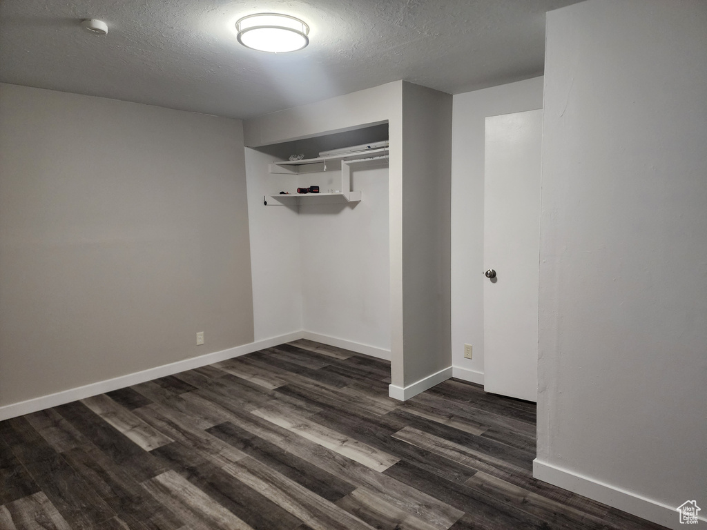 Unfurnished room with a textured ceiling and dark hardwood / wood-style flooring