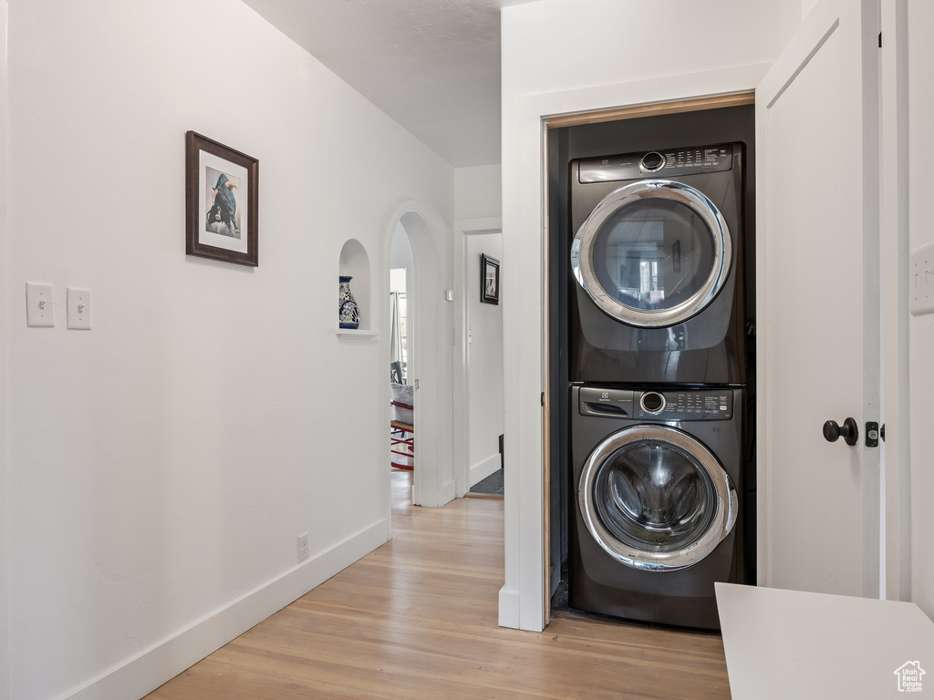 Laundry area featuring stacked washer / dryer and light hardwood / wood-style flooring