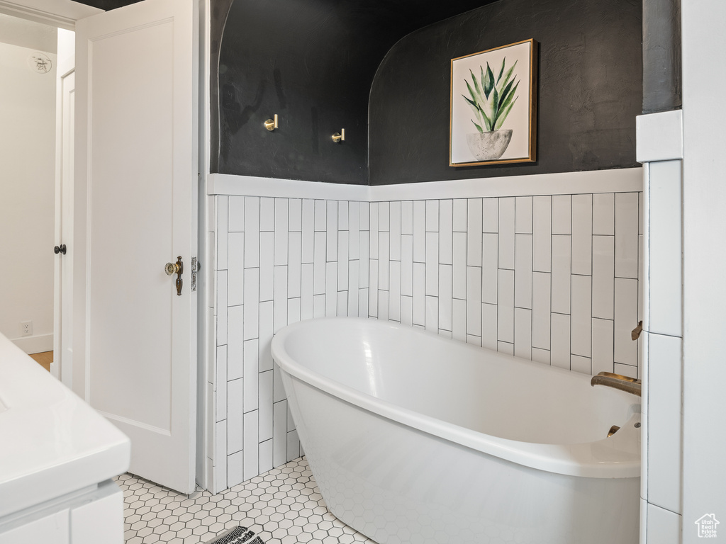 Bathroom with tile walls, a bathing tub, and tile floors
